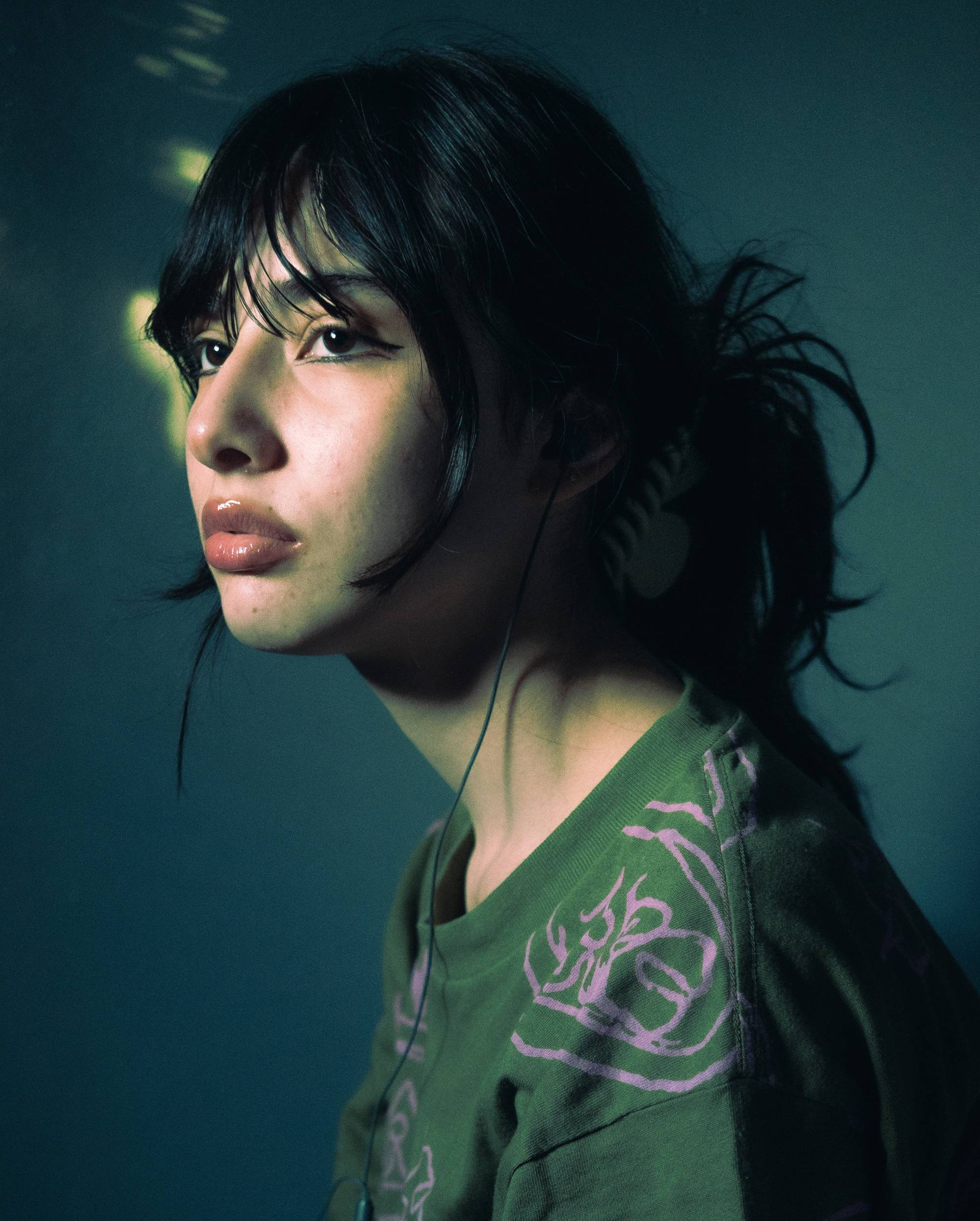 Color photograph portrait of a person with dark hair and green shirt.